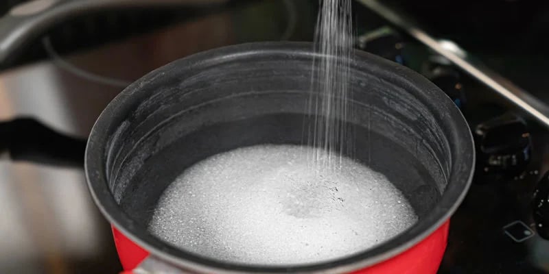 Unisci acqua e zucchero nella pentola e scalda a fuoco medio finché lo zucchero non si sarà completamente sciolto.