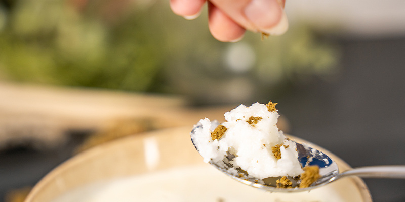Versate l'olio di cocco in un cucchiaio, poi aggiungete l'hashish frammentato.